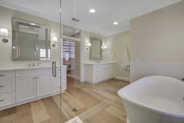 bathroom featuring hardwood / wood-style floors, vanity, a tub to relax in, and crown molding