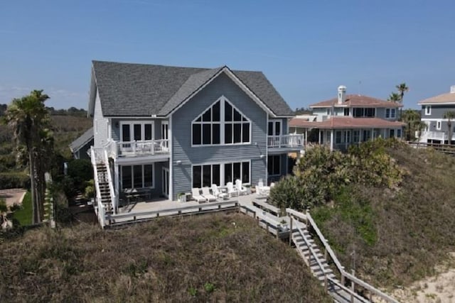 back of property featuring a balcony and a wooden deck