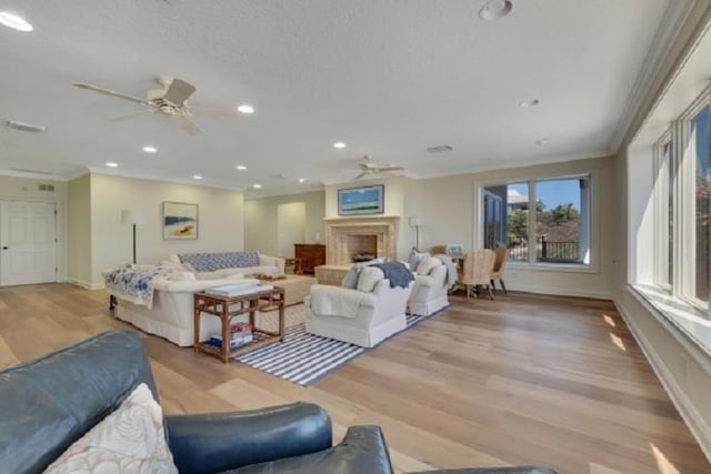 living room with light wood-type flooring, ceiling fan, and ornamental molding