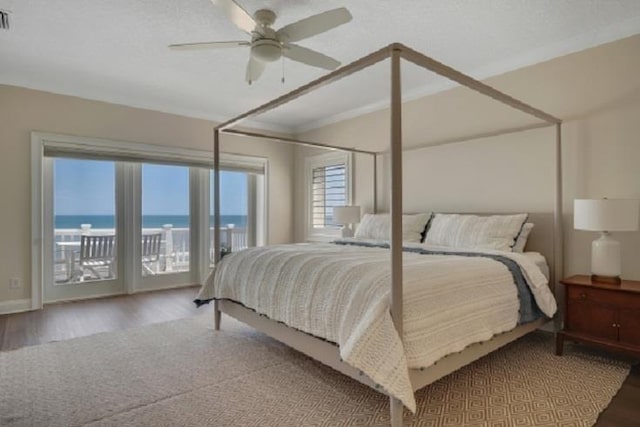 bedroom with access to exterior, a water view, hardwood / wood-style flooring, and ceiling fan