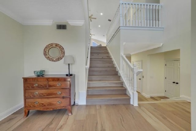 stairway with crown molding, hardwood / wood-style floors, and ceiling fan