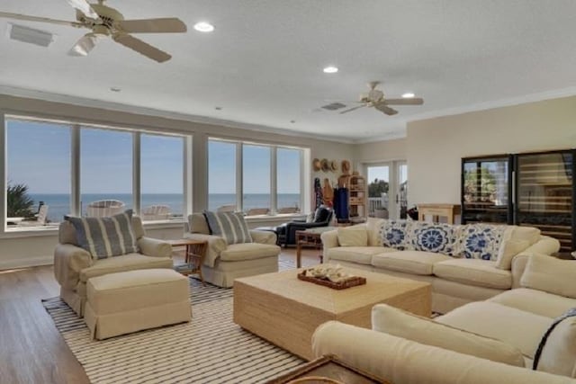 living room featuring ceiling fan, a healthy amount of sunlight, a water view, and light wood-type flooring