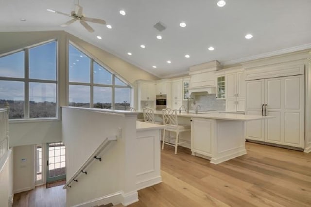 kitchen with oven, lofted ceiling, an island with sink, and a wealth of natural light