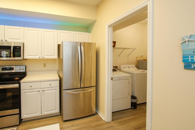 35103 Harbour Vista Cir, Saint Augustine, FL 32080 - kitchen featuring light wood-style floors, white cabinets, stainless steel appliances, and washing machine and dryer