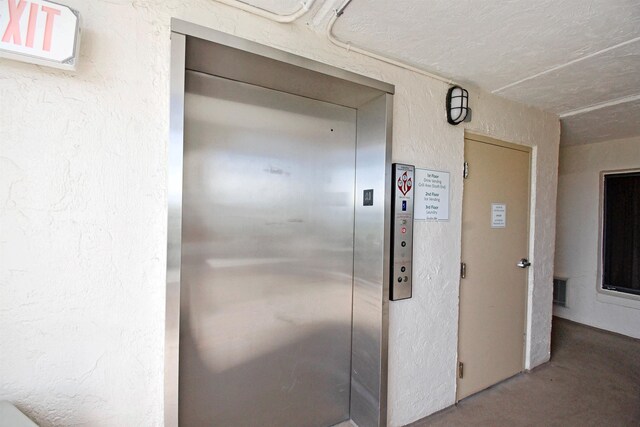 hallway with elevator and concrete floors