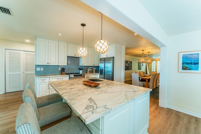 277 W River Rd, Palatka, FL 32177 - kitchen with visible vents, light wood-type flooring, white cabinets, stainless steel appliances, and a sink