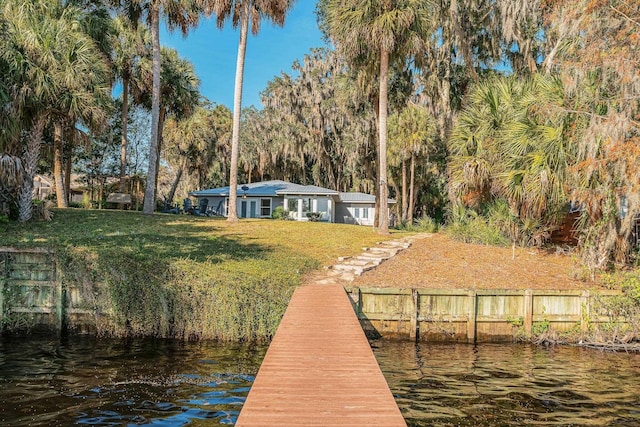 view of dock featuring a yard, fence, and a water view