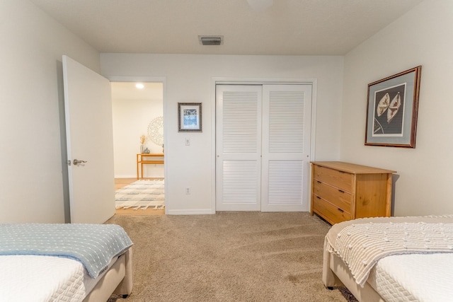 bedroom with light carpet, visible vents, baseboards, and a closet