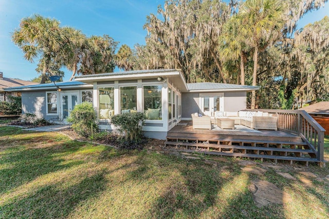 back of house featuring french doors, a yard, a wooden deck, outdoor lounge area, and metal roof