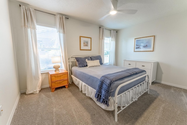 bedroom featuring a textured ceiling, multiple windows, baseboards, and light carpet