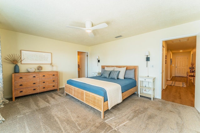 carpeted bedroom with baseboards, a ceiling fan, visible vents, and a textured ceiling