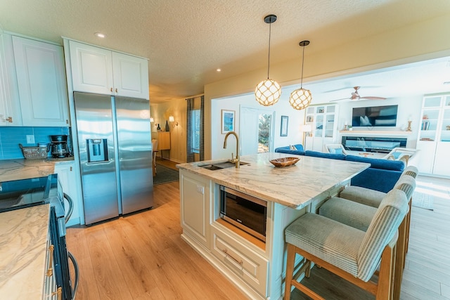 kitchen featuring a breakfast bar, light wood-style flooring, stainless steel appliances, and a sink