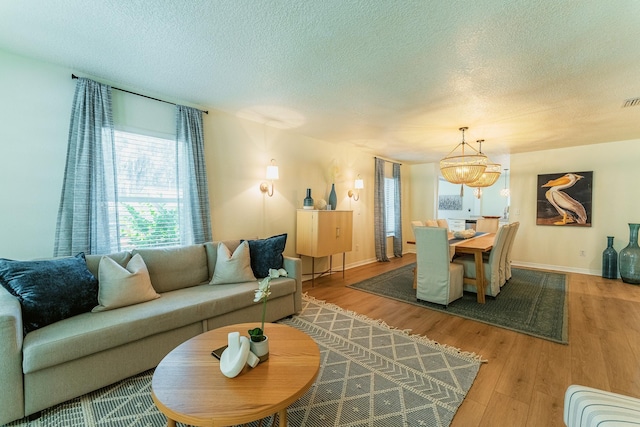 living area featuring visible vents, a textured ceiling, baseboards, and wood finished floors