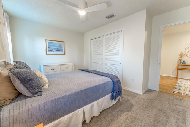 carpeted bedroom with a closet, baseboards, visible vents, and ceiling fan