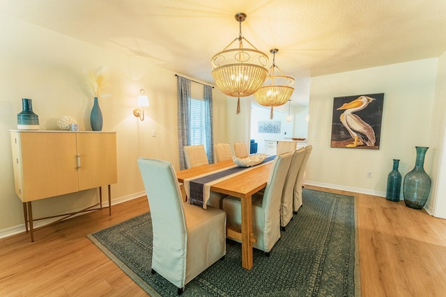 dining space with baseboards, light wood-style floors, and a chandelier