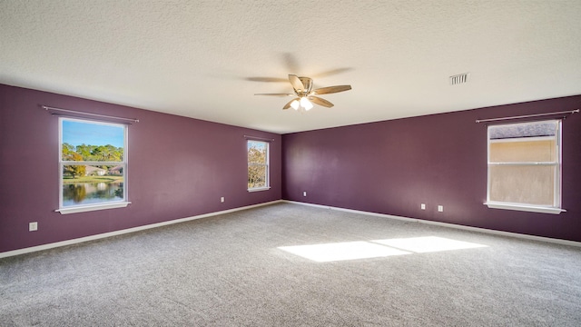 carpeted empty room featuring ceiling fan and a textured ceiling