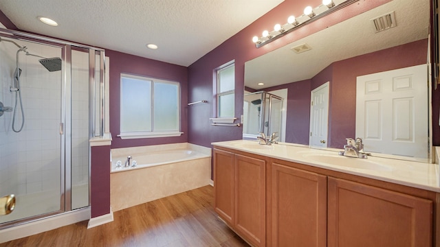 bathroom featuring hardwood / wood-style flooring, vanity, plus walk in shower, and a textured ceiling