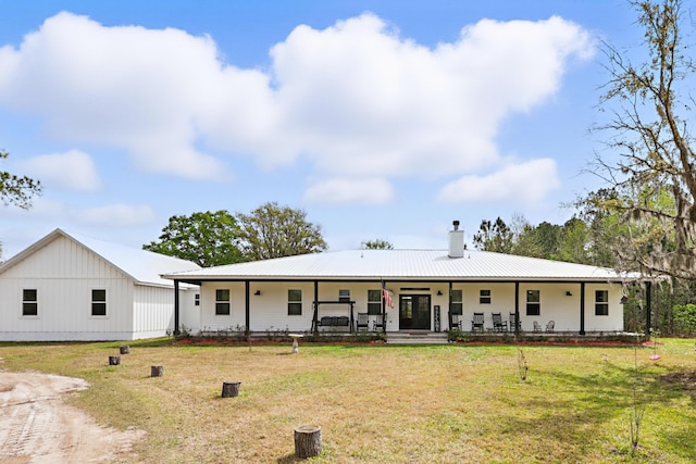 view of front of house with a porch, metal roof, a chimney, and a front lawn