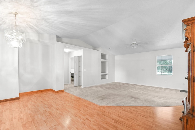 885 Wildwood Dr, Saint Augustine, FL 32086 - unfurnished living room with built in shelves, vaulted ceiling, a ceiling fan, a chandelier, and light wood-style floors