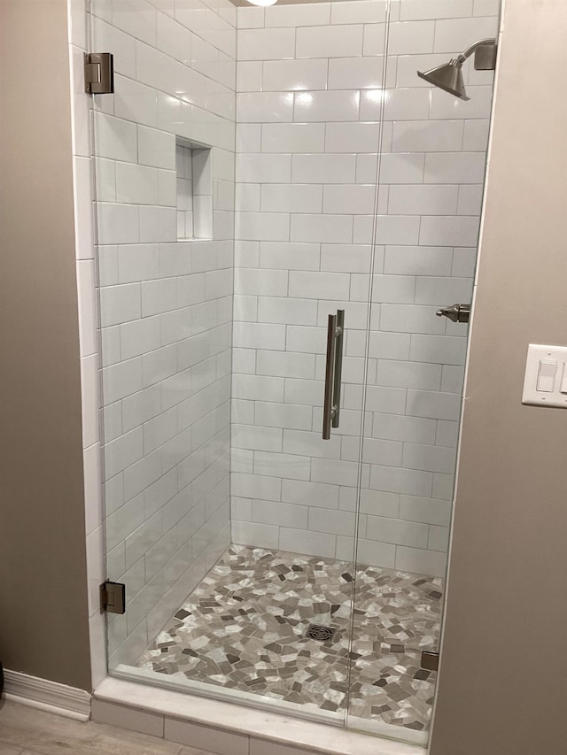 bathroom with hardwood / wood-style flooring and an enclosed shower