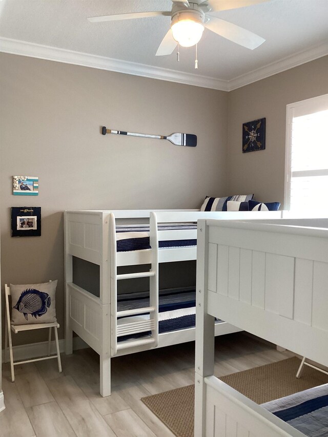 bedroom with ceiling fan, ornamental molding, and light hardwood / wood-style flooring