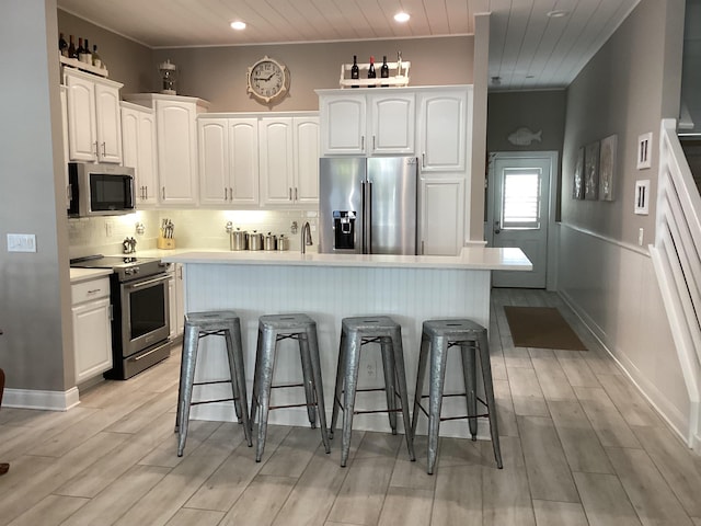 kitchen featuring white cabinets, a kitchen breakfast bar, a kitchen island, and appliances with stainless steel finishes