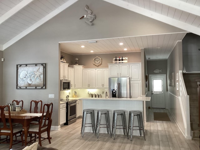 kitchen featuring appliances with stainless steel finishes, a kitchen breakfast bar, backsplash, white cabinetry, and a kitchen island