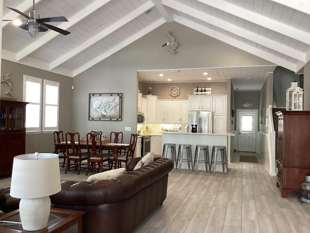 living room with beam ceiling, ceiling fan, light hardwood / wood-style flooring, and high vaulted ceiling