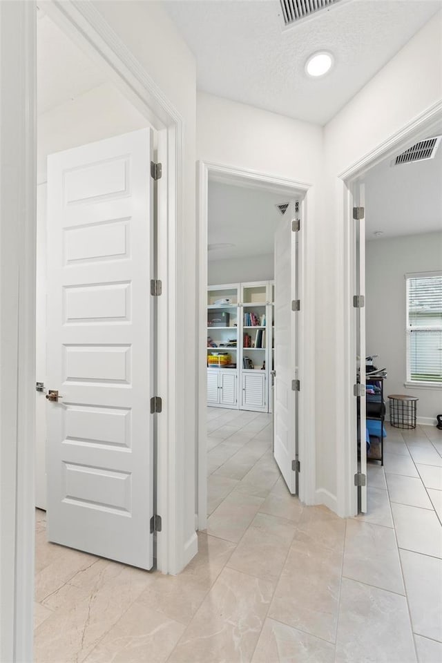 hallway featuring baseboards, visible vents, and a textured ceiling