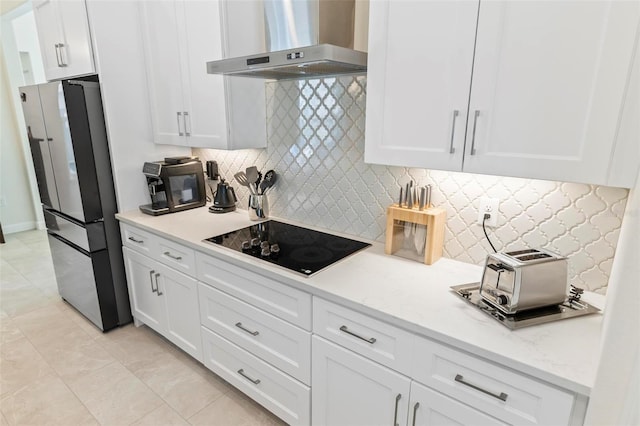 kitchen with backsplash, wall chimney range hood, freestanding refrigerator, white cabinetry, and black electric cooktop