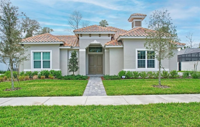 mediterranean / spanish home with a front lawn, a tiled roof, and stucco siding