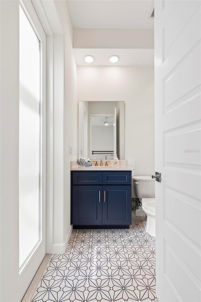 bathroom with visible vents, toilet, a healthy amount of sunlight, and vanity