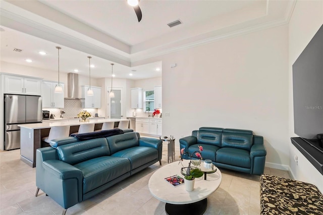 living area featuring visible vents, a raised ceiling, and crown molding