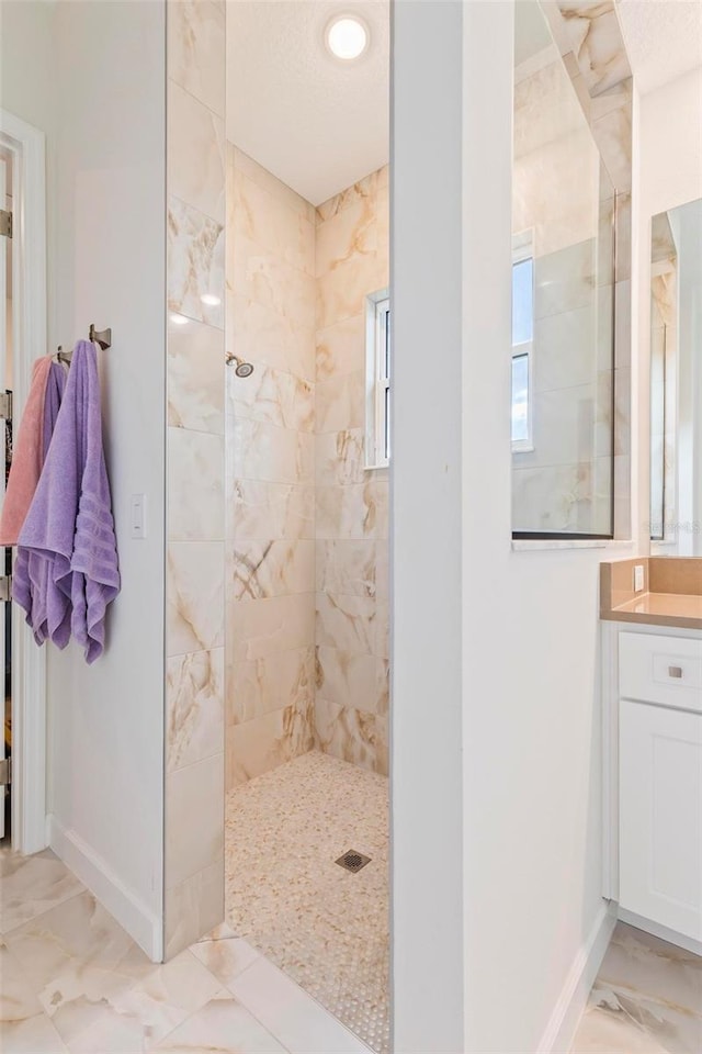 full bath with vanity, a walk in shower, marble finish floor, and baseboards