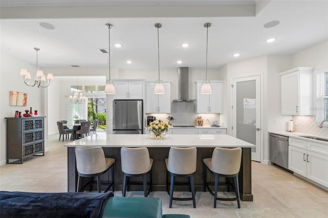 kitchen featuring stainless steel appliances, light countertops, wall chimney range hood, and a sink