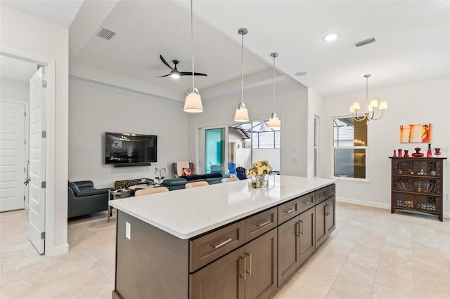 kitchen featuring visible vents, a kitchen island, light countertops, and a tray ceiling