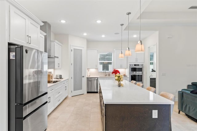 kitchen with a kitchen island, a sink, decorative backsplash, light countertops, and appliances with stainless steel finishes