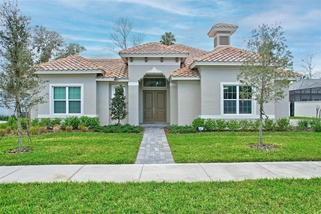 mediterranean / spanish home with a front lawn, a tile roof, and stucco siding