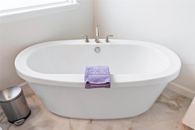 bathroom featuring baseboards and a freestanding bath