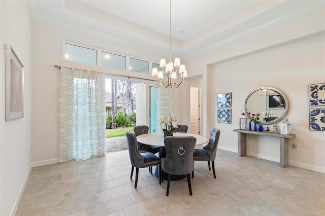 dining area featuring a chandelier, a raised ceiling, and baseboards