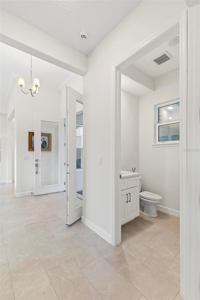 bathroom featuring visible vents, baseboards, toilet, a notable chandelier, and vanity