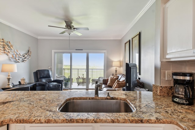 kitchen featuring white cabinetry, ceiling fan, ornamental molding, and sink