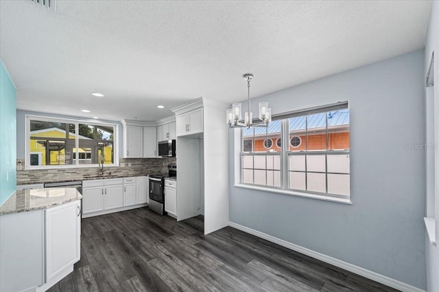 342 Euclid Ave, Daytona Beach, FL 32118 - kitchen featuring appliances with stainless steel finishes, tasteful backsplash, a chandelier, light stone countertops, and white cabinetry