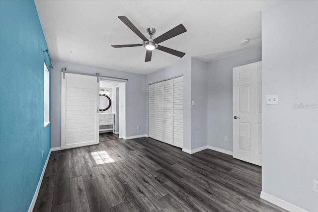 342 Euclid Ave, Daytona Beach, FL 32118 - unfurnished bedroom with a barn door, dark wood-type flooring, ceiling fan, and ensuite bathroom