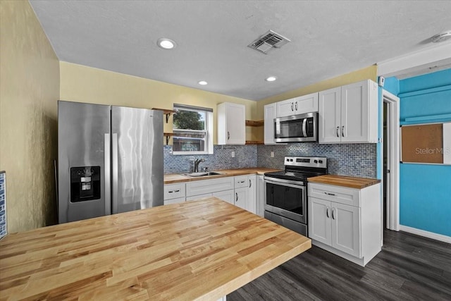 342 Euclid Ave, Daytona Beach, FL 32118 - kitchen featuring appliances with stainless steel finishes, wooden counters, dark wood finished floors, white cabinets, and tasteful backsplash