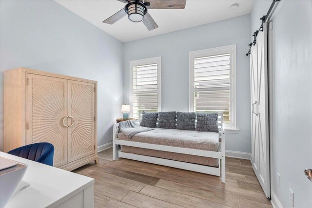 97 Paranza Trce, Saint Augustine, FL 32095 - bedroom with light wood-type flooring, a barn door, and a ceiling fan