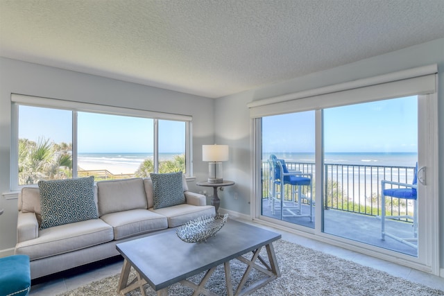 8550 S A1A # 102, Saint Augustine, FL 32080 - living room featuring baseboards, a view of the beach, tile patterned flooring, a textured ceiling, and a water view