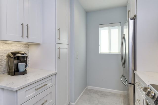 8550 S A1A # 102, Saint Augustine, FL 32080 - kitchen featuring white cabinets, baseboards, stainless steel appliances, backsplash, and light stone counters