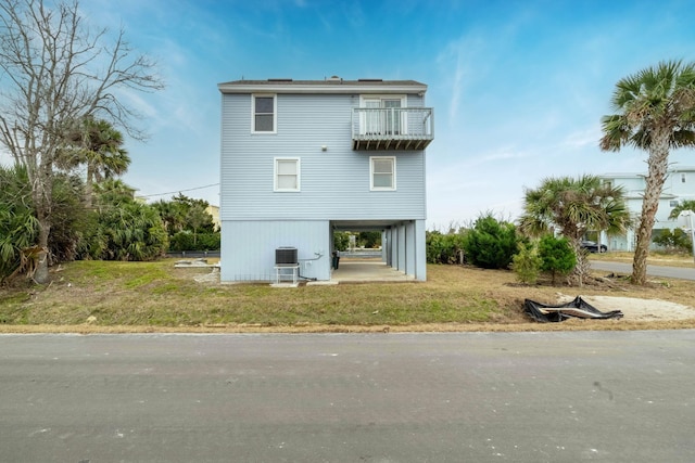 rear view of house featuring cooling unit, a yard, and a balcony