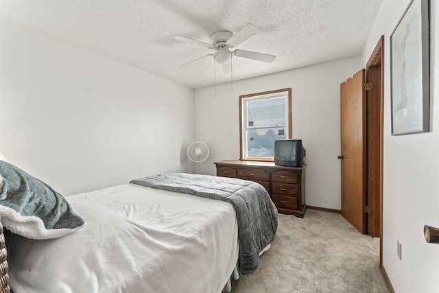 bedroom with baseboards, a ceiling fan, a textured ceiling, and light colored carpet